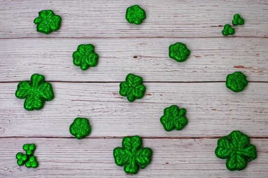 Glitter Covered Four Leaf Clovers in a Diagonal Pattern on a White Wooden Background