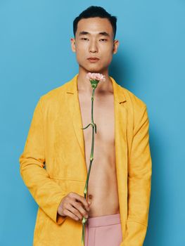 A guy with a beautiful flower in his hands on a blue background in a yellow coat. High quality photo