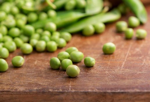 RAW baby peas in small white bowl, over retro wooden boards. Close-up