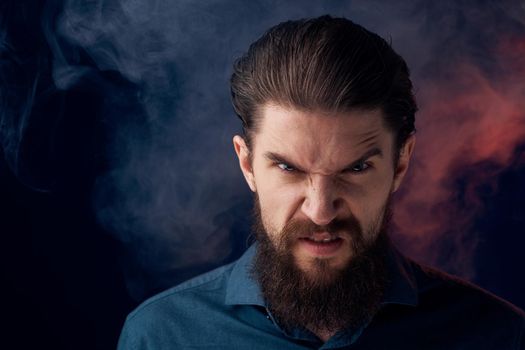 Emotional bearded man angry look shirt smoke in the background. High quality photo