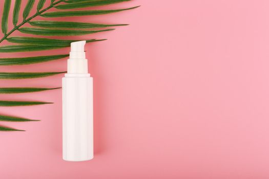 Minimalistic flat lay with face cream or lotion for daily skin care against pink background with palm leaf with copy space. High quality photo