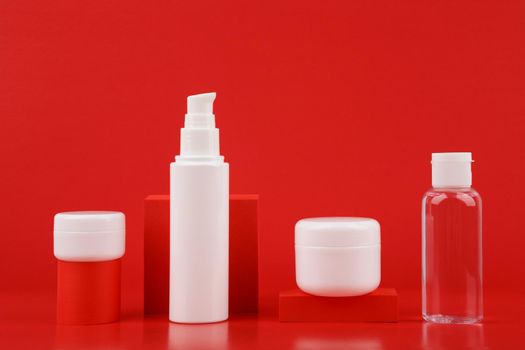 Set of cosmetic products against red background with geometric props. Concept of beauty routine and skin care or anti aging treatment