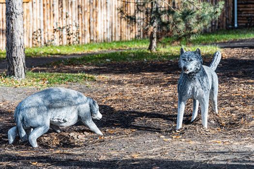 Statues of two gray wolfs on small glade