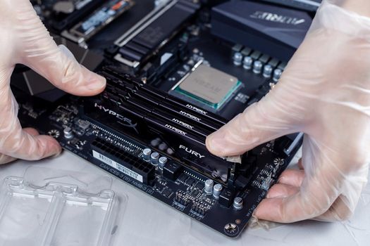 Moscow, Russia -25 Dec 2020: Installing ram memory module on desktop computer motherboard closeup