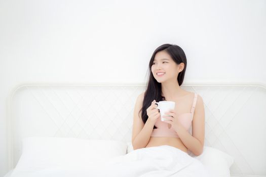 Beautiful young asian sexy woman in underwear drinking coffee in the morning on bed at bedroom, asia girl with seductive figure fit drinking beverage for relax after wake up, lifestyle concept.