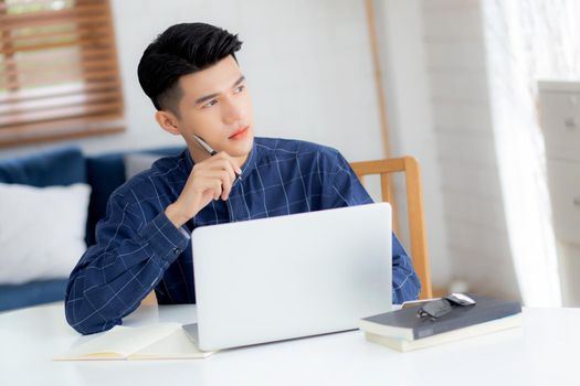 Young asian business man planning working and using laptop computer on desk at home, notes about finance, male study and learning, businessman thinking idea, business and communication concept.