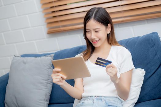 Young asian woman smiling holding credit card shopping online with tablet computer buying and payment, girl using debit card purchase or transaction of finance, lifestyle and e-commerce concept.