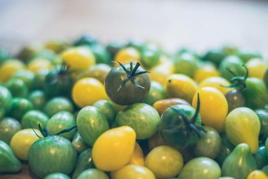 Close up of cocktail tomatoes on wooden plate, yellow and green