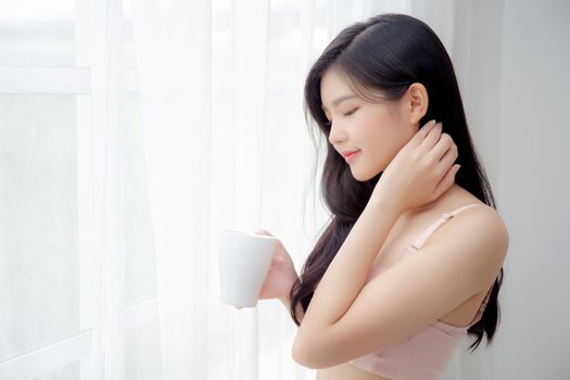 Beautiful young asian sexy woman in underwear drinking coffee near windows in the morning, girl with seductive figure fit drinking beverage for relax and resting after wake up, lifestyle concept.