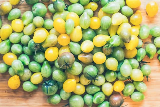 Close up of cocktail tomatoes on wooden plate, yellow and green