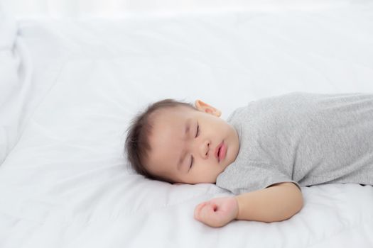Portrait of asian little baby girl sleeping on bed in the bedroom at home, newborn napping with cozy and relax, infant innocence in bedtime, happy toddler cute, growth of child and emotion, indoors.