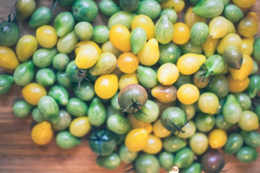 Close up of cocktail tomatoes on wooden plate, yellow and green