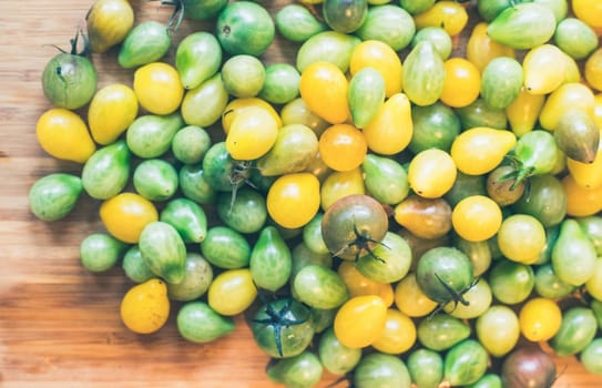 Close up of cocktail tomatoes on wooden plate, yellow and green