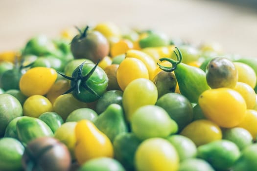 Close up of cocktail tomatoes on wooden plate, yellow and green