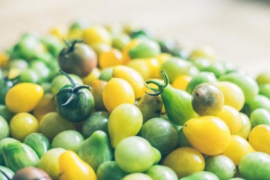 Close up of cocktail tomatoes on wooden plate, yellow and green