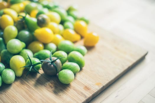 Close up of cocktail tomatoes on wooden plate, yellow and green