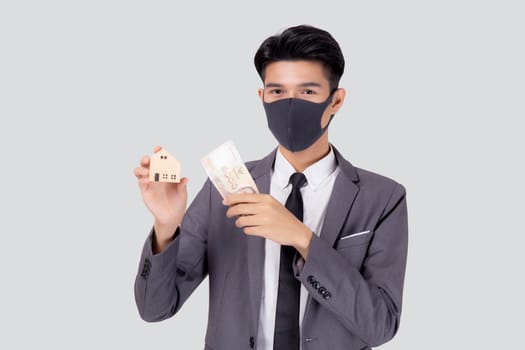 Young asian businessman in face mask holding money Thai and home isolated on white background, pandemic and crisis of economic, business man and investment property during disease covid-19.
