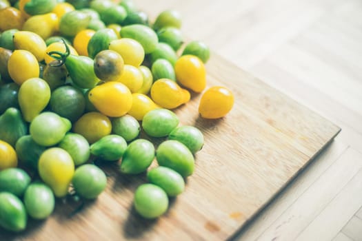 Close up of cocktail tomatoes on wooden plate, yellow and green