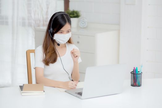 Young asian woman wearing headphone study online with e-learning on desk, girl wearing headset learning to internet with laptop computer at home, new normal, distance education and training.