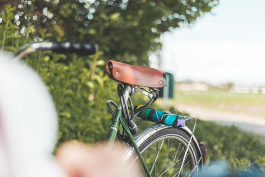 Closeup picture of brown vintage bicycle seat outdoors, blurred background