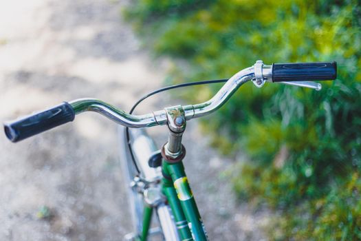 Closeup picture of a vintage bicycle handlebar and breaks outdoors, blurred background