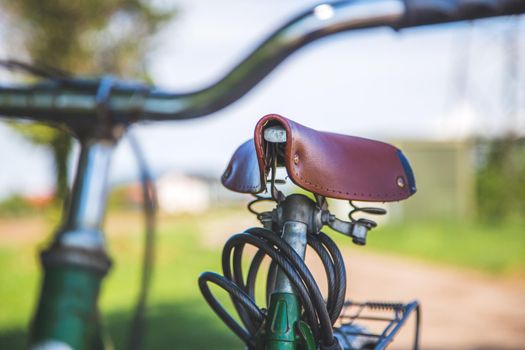 Closeup picture of brown vintage bicycle seat outdoors, blurred background