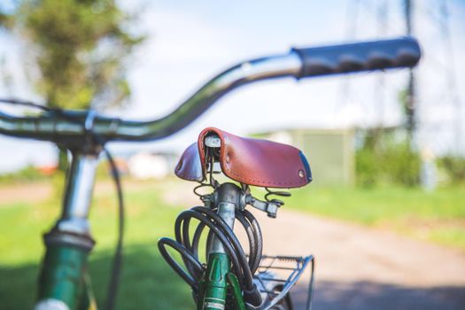 Closeup picture of brown vintage bicycle seat outdoors, blurred background