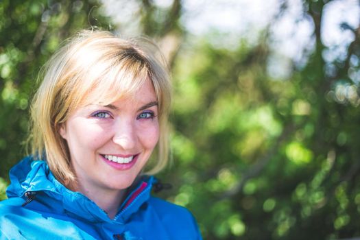 Portrait of attractive young girl outdoors, spring time, blurry green background