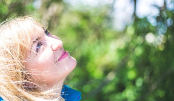 Portrait of attractive young girl outdoors, spring time, blurry green background