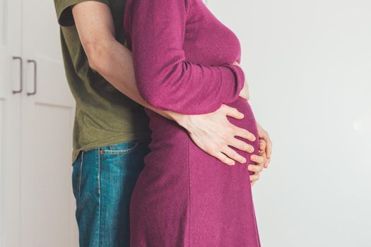 Close up of pregnant mother and father, hugging the tummy, Caucasian