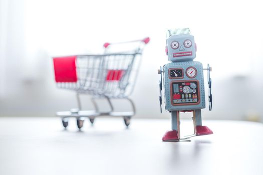 Online-Shopping concept: Toy robot and Miniature shopping cart