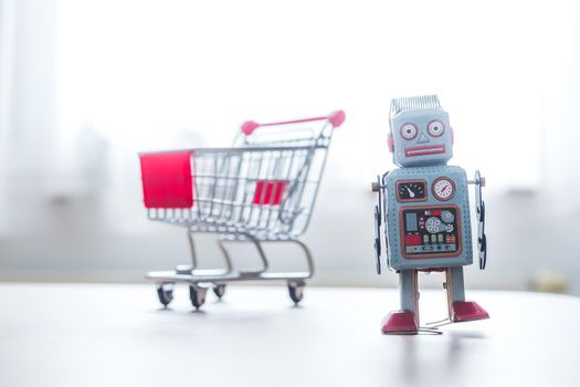 Online-Shopping concept: Toy robot and Miniature shopping cart
