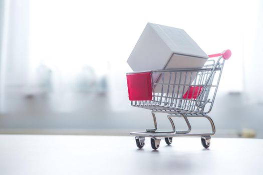 Online-Shopping and parcel service concept: Miniature shopping cart and white box