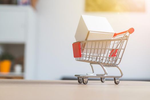 Online-Shopping and parcel service concept: Miniature shopping cart and white box