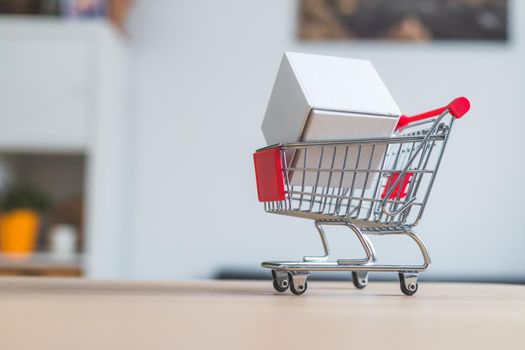 Online-Shopping and parcel service concept: Miniature shopping cart and white box