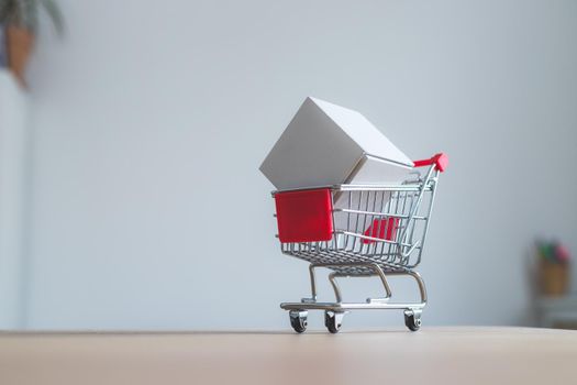 Online-Shopping and parcel service concept: Miniature shopping cart and white box