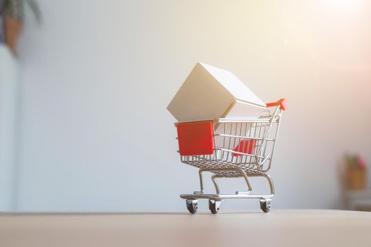 Online-Shopping and parcel service concept: Miniature shopping cart and white box