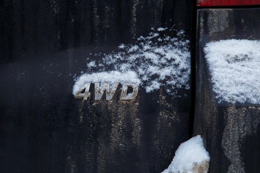 an abbreviation 4wd - four wheel drive - on dirty black car back, with snow