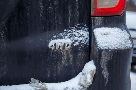 an abbreviation 4wd - four wheel drive - on dirty black car back, with snow