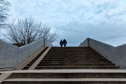 Two persons walking on the concrete bridge over the street