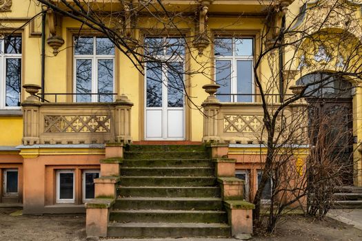 Facade of renovated tenement house with old stairs and terrace