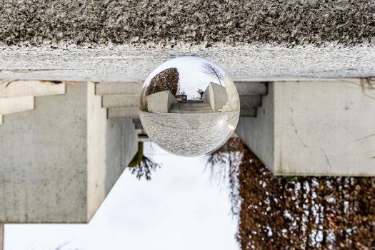 Small concrete stairs in city streets with bushes around reflected in crystal glassy lensball