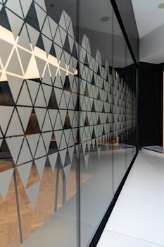 High glassy wall with small triangle stickers on it in long corridor