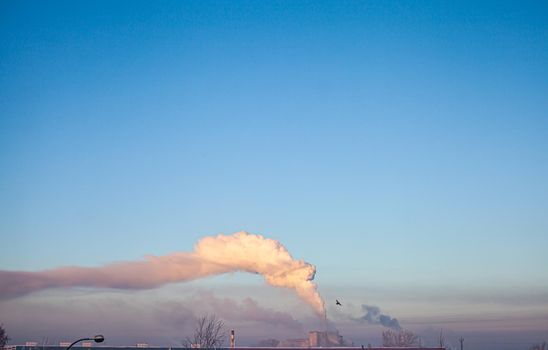 White thick smoke from the boiler room chimney. Smoke against the blue sky. Air pollution. Heating of the city. Industrial zone.