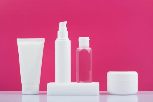 Still life with set of beauty products in a row on white glossy table against bright pink background. Concept of skin care and beauty . High quality photo