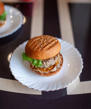 Sandwich with cutlet, cheese and green salad on a plate in the kitchen. Sandwich at home. The concept of healthy and unhealthy food.