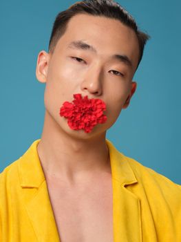 A man in a yellow jacket with a flower in his teeth on a blue background. High quality photo