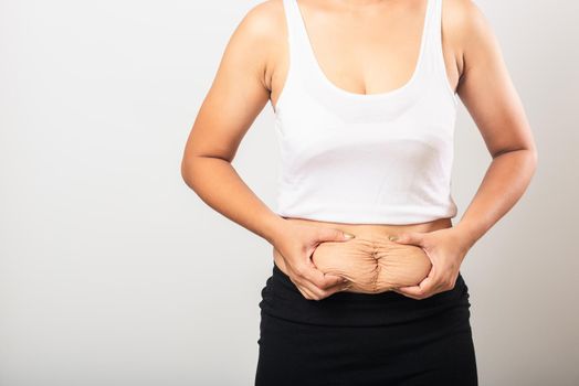 Close up of Asian mother woman showing stretch mark loose lower abdomen skin she fat after pregnancy baby birth, studio isolated on white background, Healthy belly overweight excess body concept