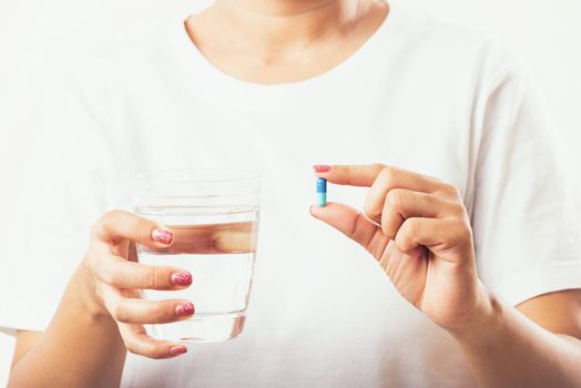 Closeup young Asian woman hold pill drugs in hand ready take medicines with a glass of water, studio shot isolated on white background, Healthcare and medical pharmacy concept