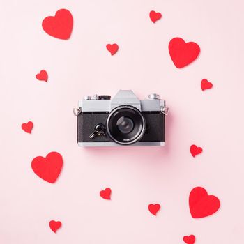 Valentines' day background. Vintage retro camera and red hearts composition greeting card love Valentines day I love photography concept on pink background with copy space. Top View from above